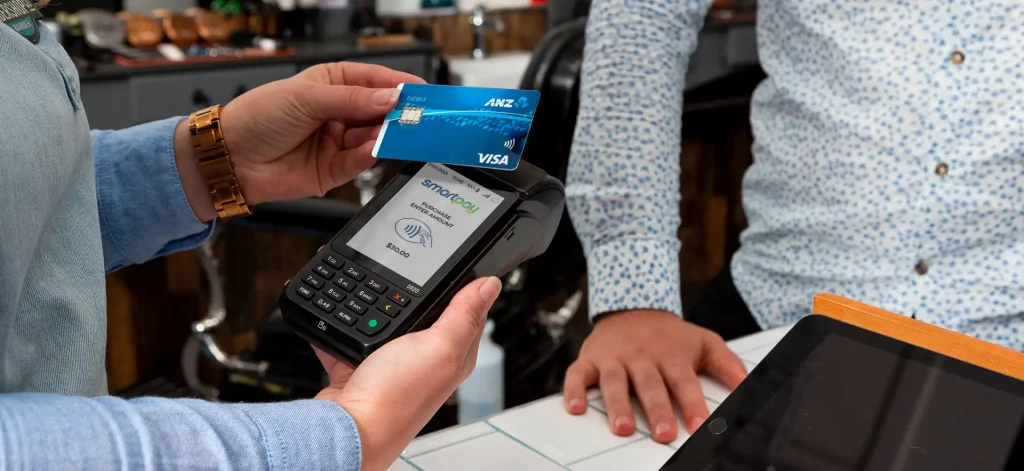 Customer paying by hovering card on EFTPOS machine.