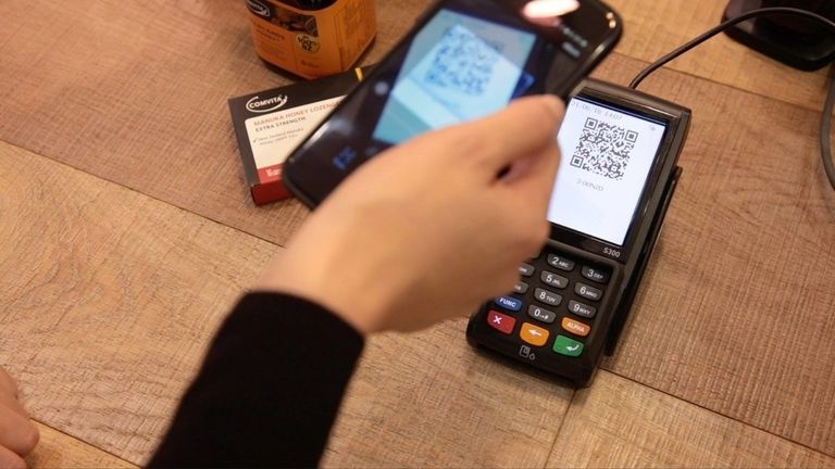 Lady scanning QR code to pay