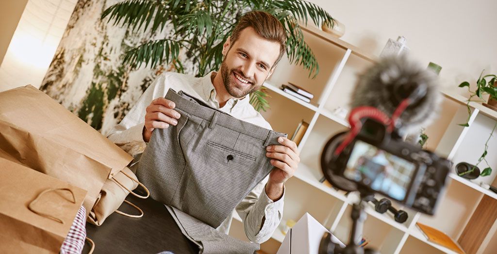 Man holding up a pair of pants in front of a camera for a photograph