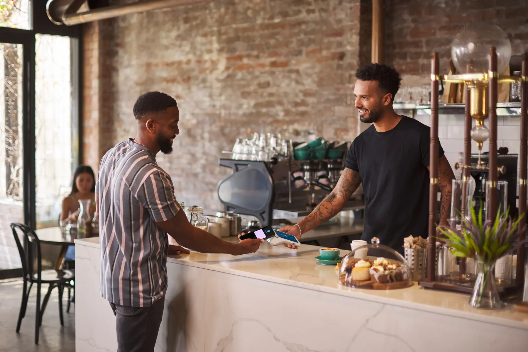 Customer paying for coffee with mobile phone in Cafe