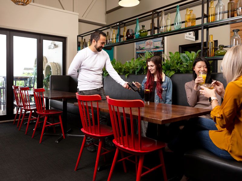 Lady paying for drink in bar while seated at table