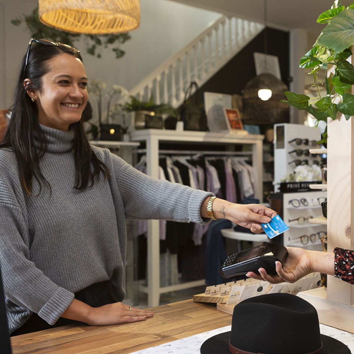 Lady paying for hat by tapping card on EFTPOS terminal