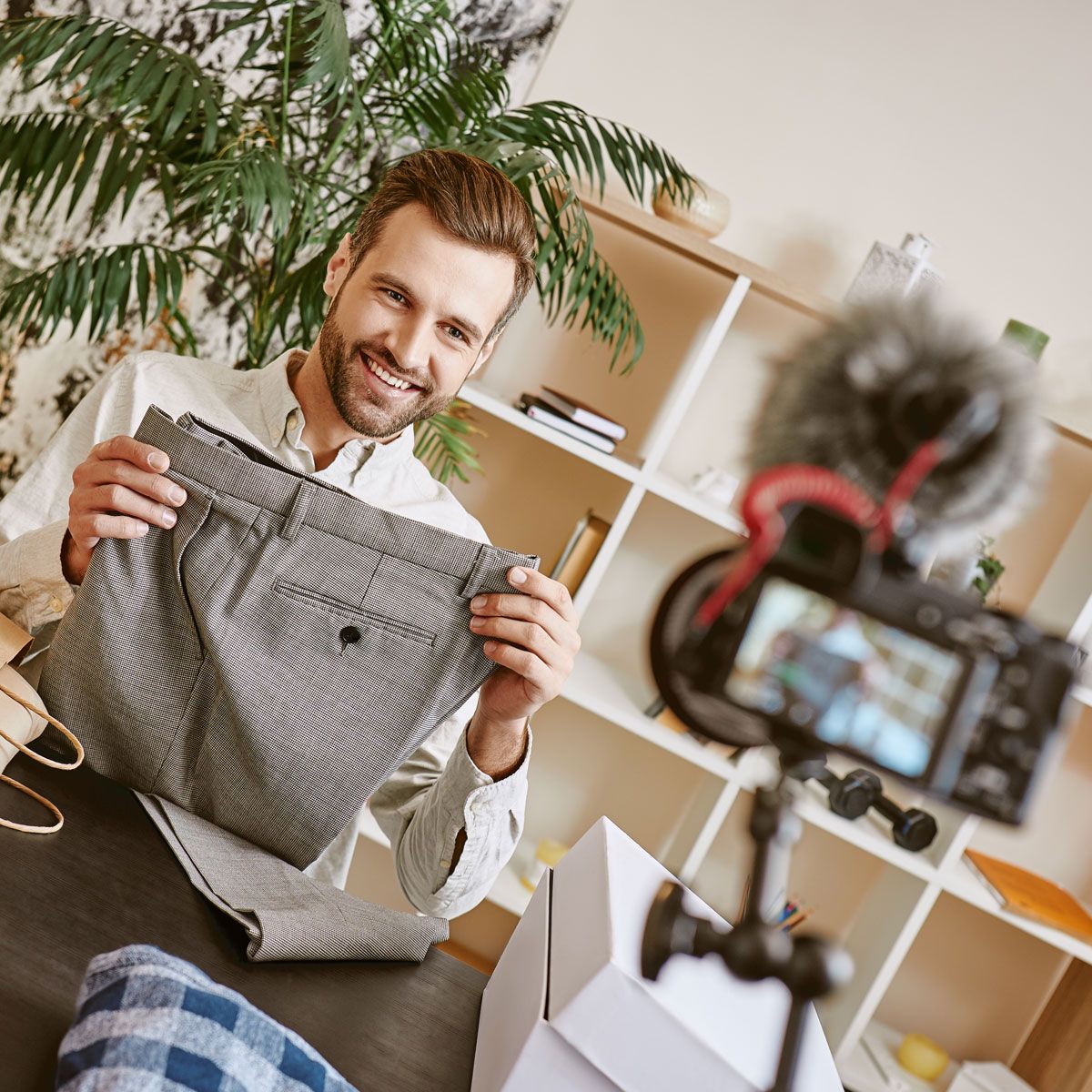 Man holding up a pair of pants in front of a camera for a photo