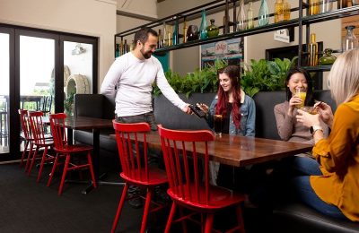 Lady paying for drink in bar while seated at table